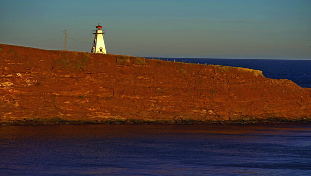 Cape Tryon lighthouse and red sandstone cliffs, in early morning light, Cape Tryon, Prince Edward Island, Canada
