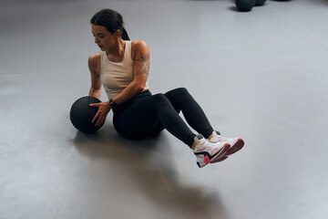 Female doing side twist exercise with medicine ball during intense functional training in gym