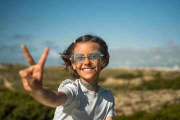 Naklejka premium Positive little child shoving victory gesture to her friend while spending time at the green nature