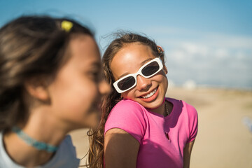 Portrait view of the two girls enjoying of the summer while sitting at the ocean beach