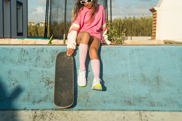 Female child sitting at the ramp with her skateboard at open air rollerdrome © Yakobchuk Olena