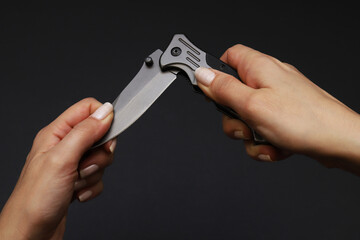 Folding knife in the hands of a woman. Close-up