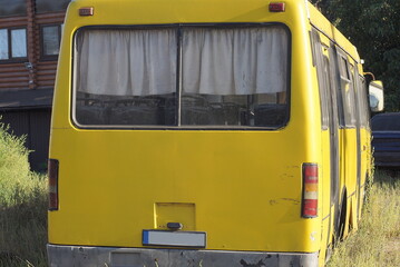 back of one big yellow bus on the street in the grass