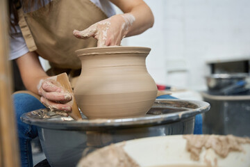 Fototapeta na wymiar Woman potter forms earthenware on a potter wheel
