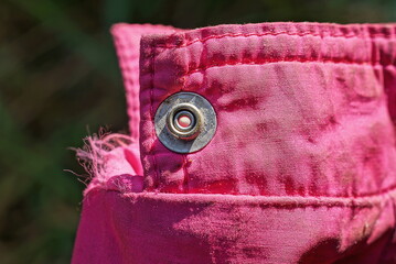 one gray metal rivet button on the pink fabric sleeve on the jacket