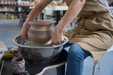 Craftswoman sits at the potter wheel and creates clay product