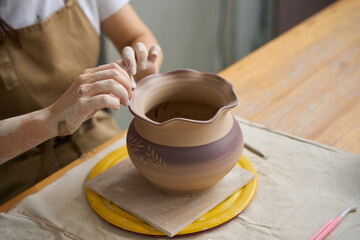 Master decorates the wavy edge of a clay vase