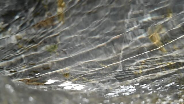 Sunlight effects from water in a rocky mountain river (slow motion, close up)