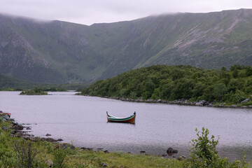 Wonderful landscapes in Norway. Nordland. Beautiful scenery of a valley with a picturesque boat in the Storvatnet lake. Rippled water in a cloudy summer day. Selective focus