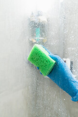 A woman cleans a shower cabin from limestone - 533034667