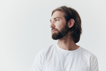 Portrait of a sad man with a black thick beard and long hair in a white t-shirt on a white isolated...