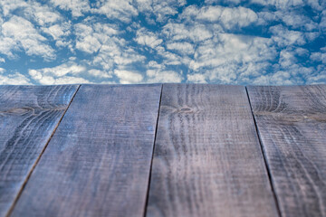 Empty wooden table and beautiful blue sky and white clouds in background. Perspective brown wooden board
