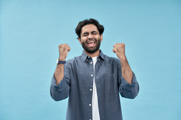 Happy excited young arab man looking at camera with winning face expression raising fists yes...