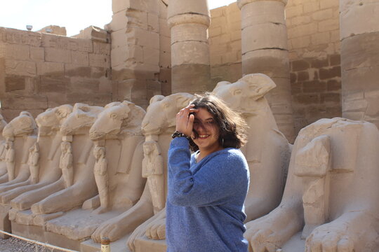 Young teenage girl in the karnak Temple with sphinx statues in the background in Luxor in Egypt