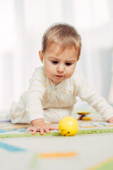 A small child crawls and plays with a ball