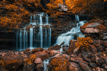 Autumn waterfall cascades through the rocks of a  fall colored forest of the Ozark Mountains of Arkansas. 