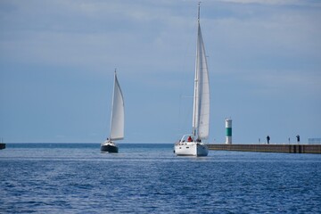 A pair of sailboats sailing down the channel 