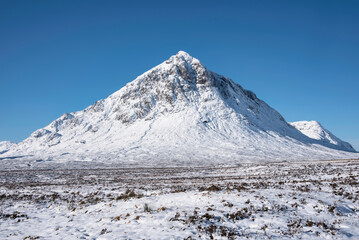 Fototapeta na wymiar Beautiful iconic landscape Winter image of Stob Dearg Buachaille Etive Mor mountain in Scottish Highlands againstd vibrant blue sky