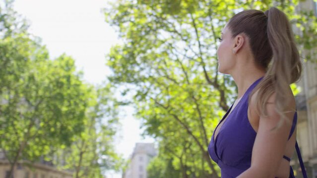 Profile shot of gorgeous young female in a purple dress walking in the city, in slow motion