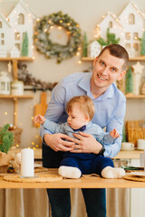 dad and baby son in the decorated for the new year kitchen. father's day