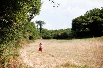 petite enfant fille marche dans la prairie en été
