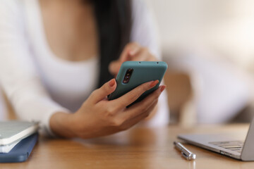 Portrait of smile asian woman freelancer using mobile phone at home office.