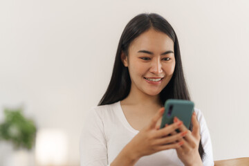 Portrait of smile asian woman freelancer using mobile phone at home office.