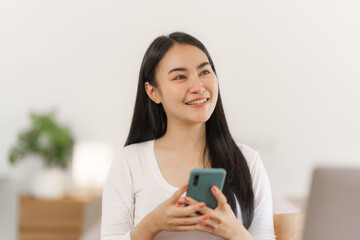 Portrait of smile asian woman freelancer using mobile phone at home office.