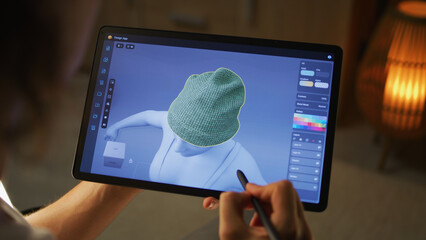 Young male 3D designer working remotely on 3D visualization of clothes in design app using digital tablet computer and stylus