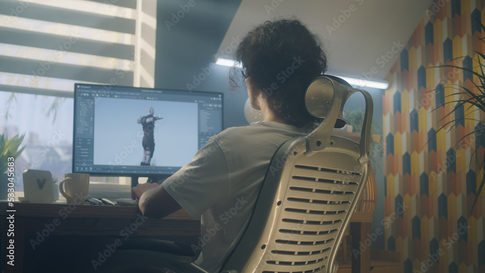 Poster male 3d designer sitting at the table at home and making animation for video game character, using m