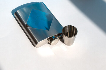 A metal flask for drinks and metal cups next to each other on a white background. For storing...