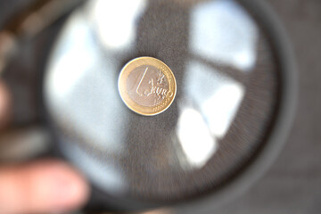 One euro coin magnified under a large magnifying glass. Rising prices or inflation in Europe. Very...