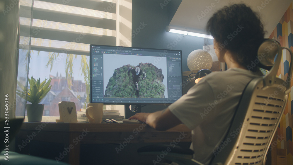 Poster male 3d designer sitting at the table at home and making animation for video game character, using m