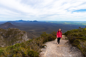 Fototapeta premium girl with pigtails on top of a mountain overlooking a green mountain range in the background; bluff knoll, highest peak in western australia
