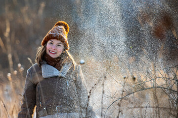 sweet girl in woollen hat, jumper, black skirt and tights enjoys the freezing cold winter and plays with snow