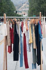 Garage sale concept – various clothes hanging on a clothing rack in the street 