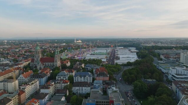 Aerial descending footage of Theresienwiese with amazing grounds of famous Oktoberfest. Revealing surrounding buildings in urban borough at twilight. Munich, Germany