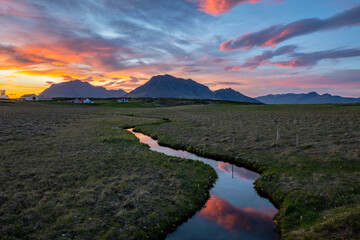 Sunset reflected in a stream flowing through farmland in Iceland