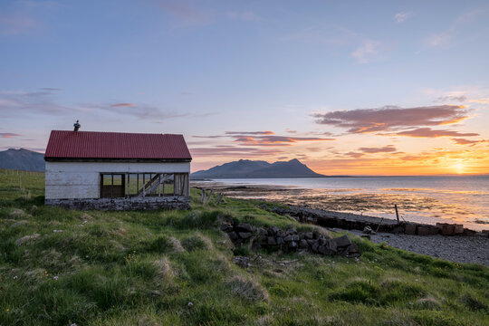 White abandoned barn / storage shed on the Icelandic coast at sunset