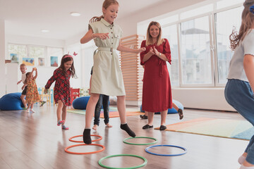 Small nursery school children with female teacher on floor indoors in classroom, doing exercise....