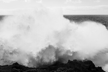 Powerful waves of the Atlantic Ocean crashing on the volcanic cliffs of Los Hervideros in Lanzarote,  Canary Islands, Spain, black and white