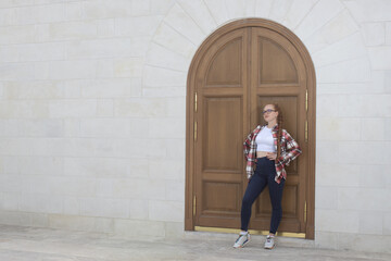 A beautiful European girl stands at a wooden door