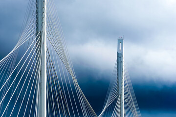 Cables and supports of white bridge  in St Petersburg against dramatic stormy sky