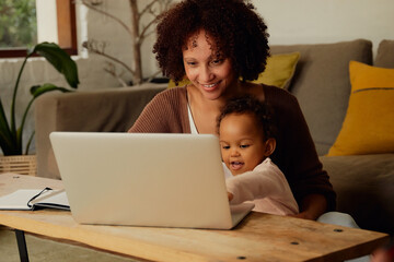 Biracial mother and daughter using laptop in living room at home