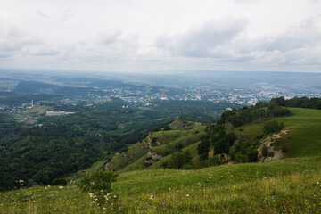 Obraz premium Panoramic top view of a beautiful valley with trees and hills and a blurred horizon against a cloudy dramatic sky in Kislovodsk russia