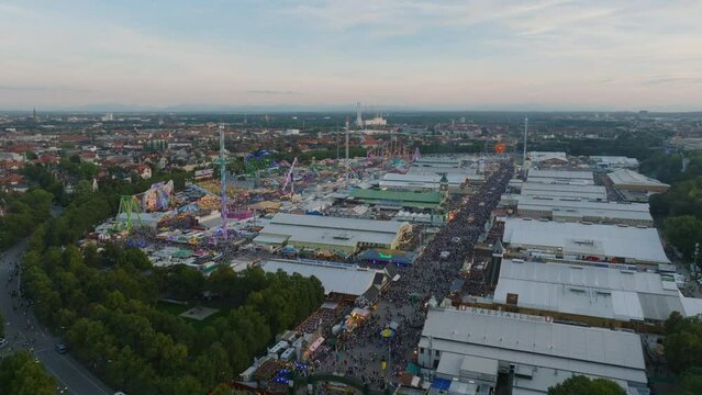 Famous beer festival and travelling carnival from height. Aerial panoramic view of crowded area of Oktoberfest at dusk. Munich, Germany