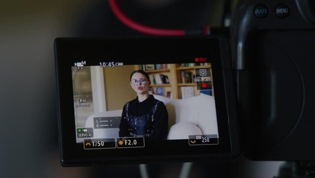 Close-up of caucasian, brunette woman in glasses within charming interior. Video recording of a lady in smart outfit as seen through camera screen. High quality 4k footage