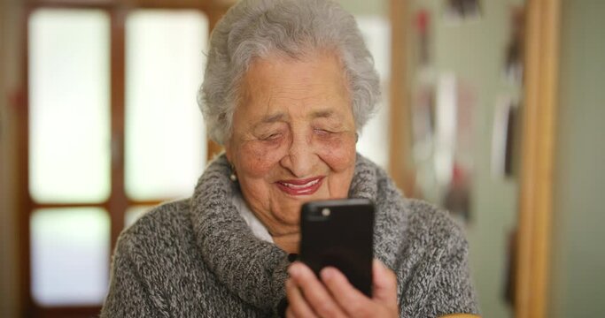Senior woman, phone news or laughing and reading internet media, video call or streaming comic digital movie. Smile or happy retirement elderly in house living room or home interior with mobile tech