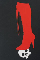 glyph or dingbat cutout of tall lace up stiletto boot layered on a white paper skull head