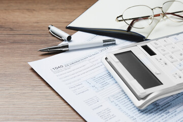 Calculator, documents and stationery on wooden table, closeup. Tax accounting